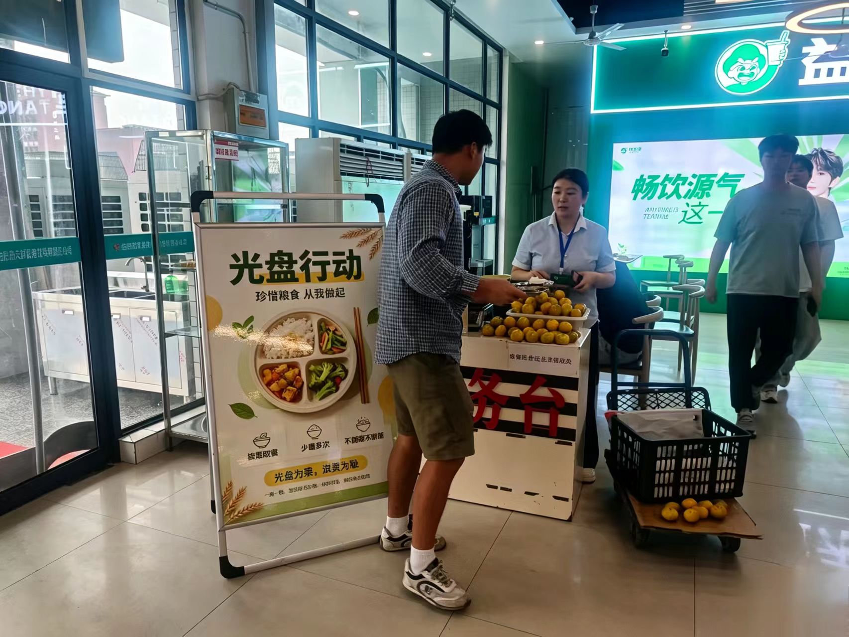 除了前端的宣传与激励，在标有“您送文明”字样的餐具回收处，同学们自觉排队，将餐盘内的残渣清理干净后分类投放。从照片中可以看到，绝大多数回收的餐盘都达到了“光盘”标准，残留物极少。食堂保洁人员在一旁协助整理，红色的回收台标语与学生们文明的举动构成了一道亮丽的风景线。
