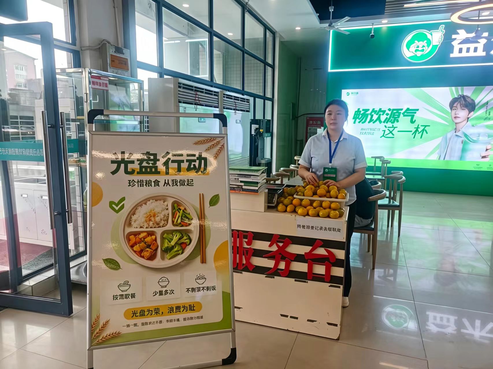活动的核心环节在于对“光盘”行为的即时激励。在四食堂内部的兑奖点，不少同学在用餐结束后，端着吃得干干净净的餐盘前来核验。工作人员认真检查后，为符合条件的同学发放小礼品或抽奖机会。桌上摆放着丰富的零食礼包，展现了活动良好的互动效果。